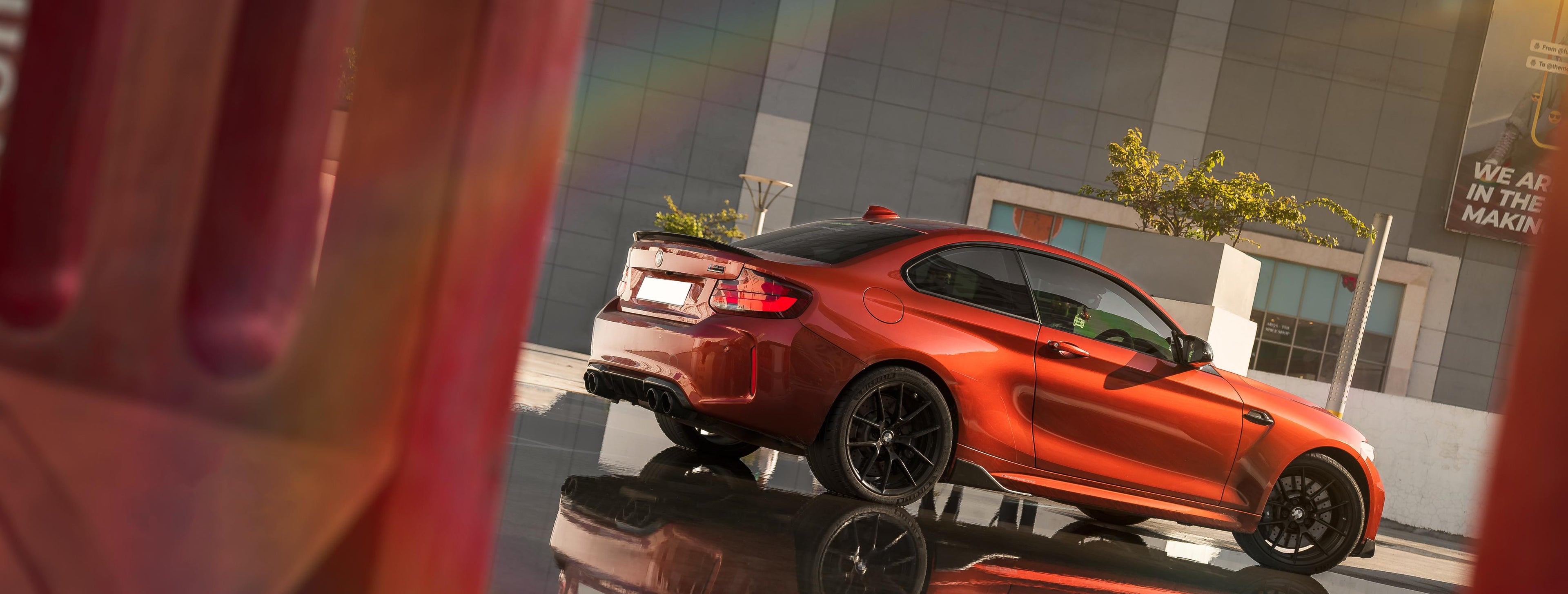 Red sports car reflected on a wet surface with a blurred background.