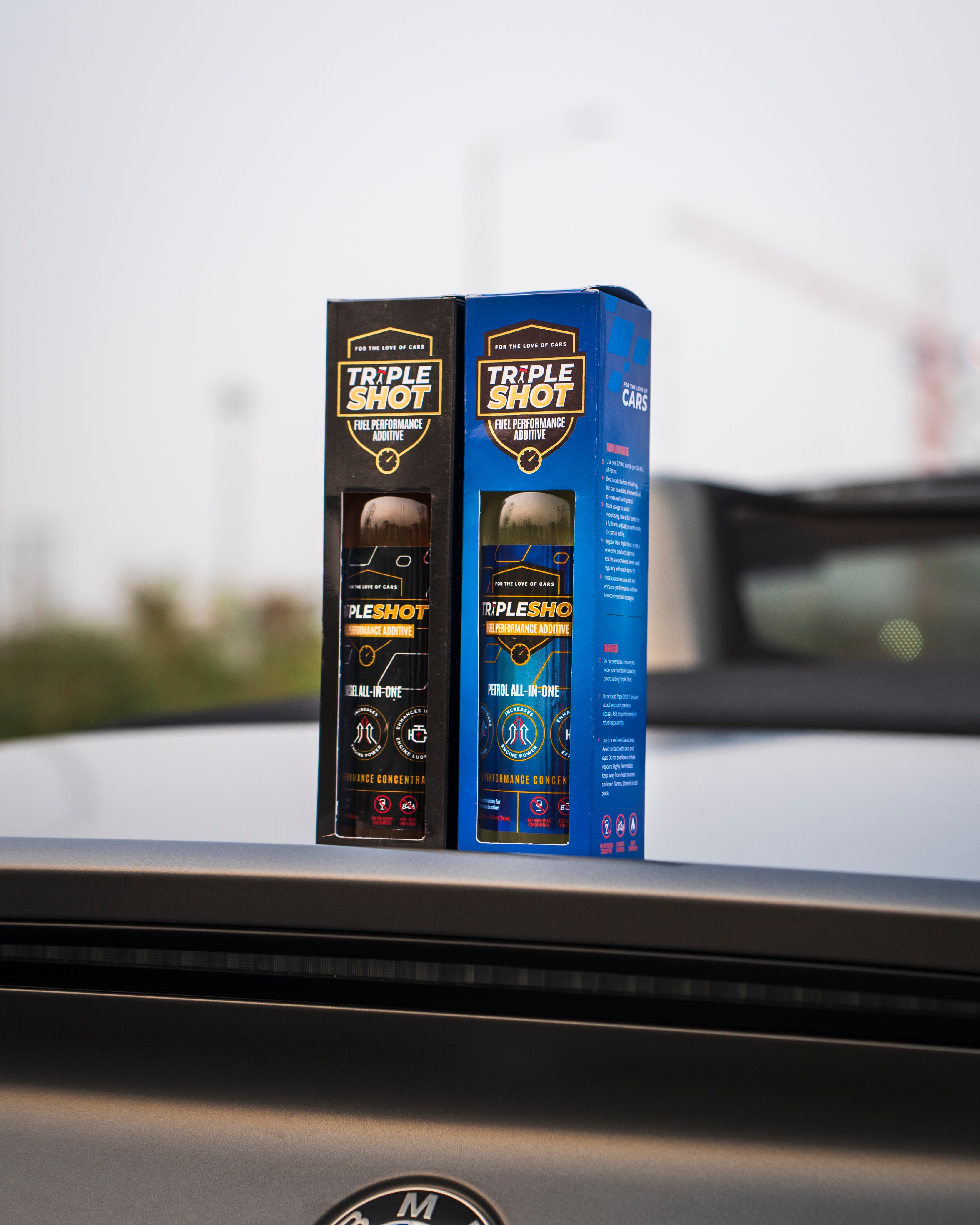Two Triple Shot car care product boxes on a car window with a blurred background